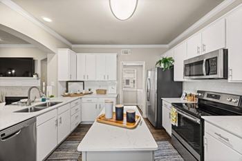 A modern kitchen with white cabinets and stainless steel appliances.